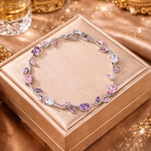 May include: A silver-toned metal bracelet featuring a vine-like design with alternating oval and marquise-cut gemstones in shades of pink, purple, and clear white. The bracelet includes a secure metal clasp closure and a delicate, flexible chain structure.