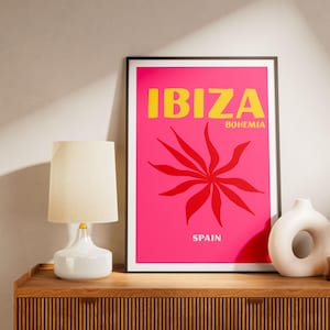 Peut inclure: Une affiche encadrée avec le mot "IBIZA" en lettres jaunes sur un fond rose vif. En dessous du mot "IBIZA" se trouve le mot "BOHEMIA" en plus petites lettres jaunes. Un motif floral rouge est au centre de l'affiche. Le mot "SPAIN" est en bas.