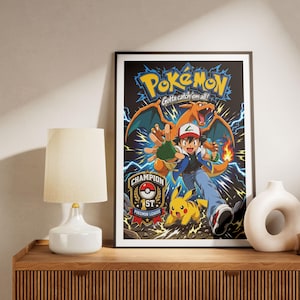 Peut inclure: Une affiche encadrée présentant une illustration colorée d'Ash Ketchum, Pikachu et Dracaufeu. Le texte indique Pokémon, Gotta catch 'em all!, et Champion 1st Pokémon League. L'œuvre inclut des éclairs bleus sur un fond sombre.