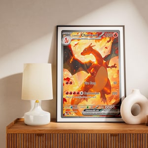 Puede incluir: Una lámina de arte mural enmarcada que presenta una gran ilustración de una carta coleccionable de la criatura naranja tipo dragón Charizard. La carta muestra el nombre Lorena's Charizard, 230 HP y los ataques Fire Fang y Destruction.