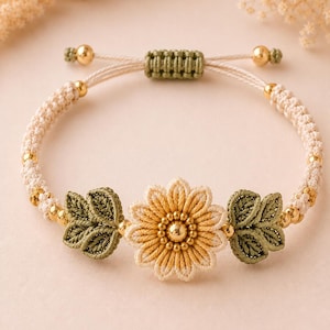 A beige and green crocheted bracelet with a central yellow flower and two green leaves, all with golden beads, on a light pink surface.