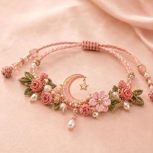 Puede incluir: Una pulsera con una media luna bordada central y un pequeño dije de estrella colgante. El diseño incluye rosas de ganchillo rosas, hojas verdes, perlas blancas y cuentas transparentes sobre un cordón rosa con cierre deslizante.