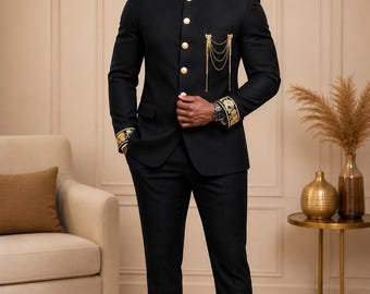May include: A black suit with gold embroidered details. The suit features a mandarin collar, gold buttons, and decorative gold chains on the chest. The cuffs and collar have gold embroidery. The suit is paired with black dress pants and shoes.