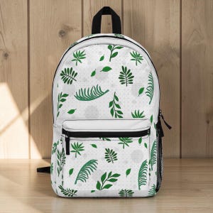 May include: White backpack with a green leaf pattern. The backpack has a black zipper, a front pocket, and a mesh side pocket. The leaves are various shapes and sizes, scattered across the white background.
