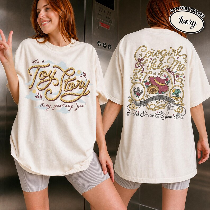 May include: An ivory t-shirt featuring a front graphic with rope-style text reading "it's a Toy Story Baby, just say yes" and a back graphic with rope-style text reading "Cowgirl like Me" and "Takes One to Know One" with a cowboy hat illustration.