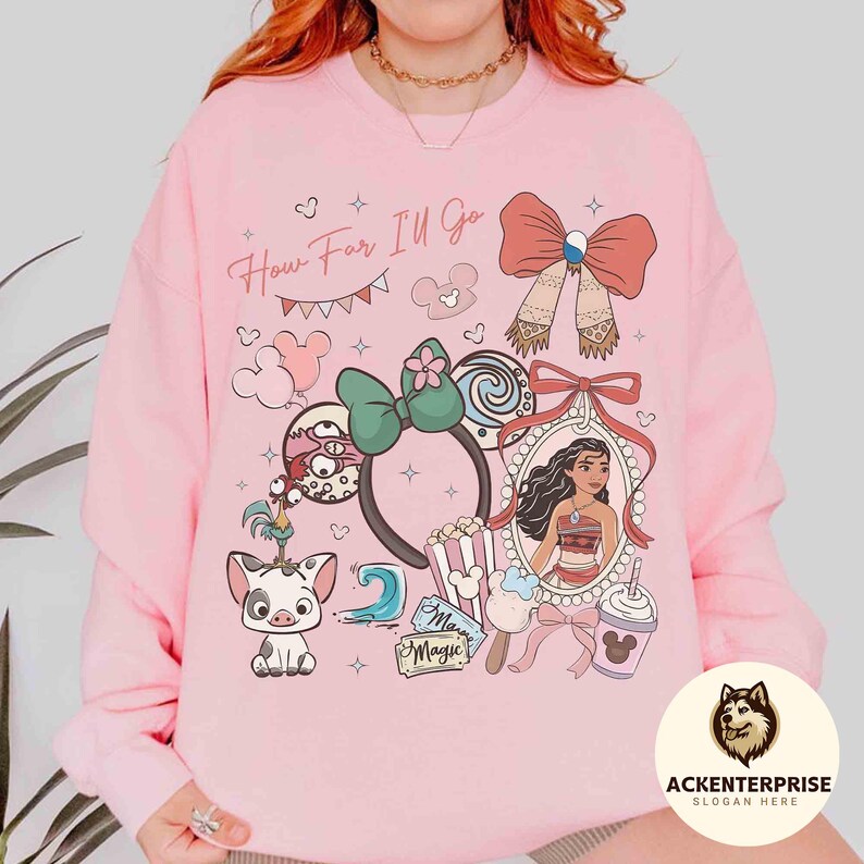 May include: Pink sweatshirt with a colorful graphic featuring a cartoon character, a bow, and the text "How Far I'll Go." The design includes a portrait, popcorn, and a Mickey Mouse ear headband.