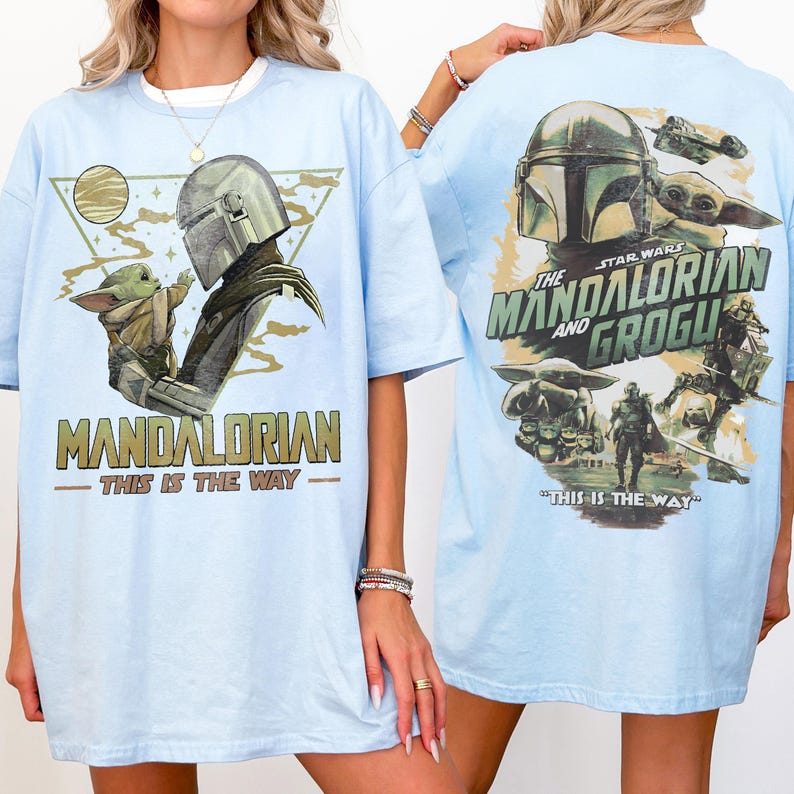 May include: Light blue t-shirt featuring a graphic of The Mandalorian and Grogu. The front design includes the text "MANDALORIAN - THIS IS THE WAY" with an image of the Mandalorian and Grogu. The back design features the text "THE STAR WARS MANDALORIAN AND GROGU - THIS IS THE WAY".