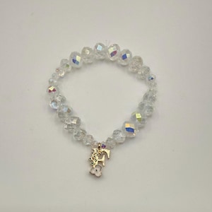 Op de afbeelding: Een heldere kralenarmband met een iriserende glans. De armband heeft een goudkleurige bedel met een bloemenontwerp en de letter "E". De kralen zijn facetgeslepen en reflecteren licht. Een delicaat sieraad.