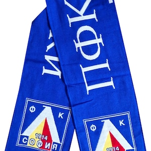 May include: Blue scarf with white text and fringe. The scarf features the text "ПФК" and the words "СОФИЯ 1914" in a square emblem with a white, red, and yellow design. A sports fan accessory.