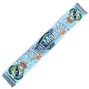 May include: Light blue Real Madrid scarf with the team's logo and the words "Real Madrid Santiago Bernabeu" printed on it. The scarf has a fringed edge and a repeating floral pattern.