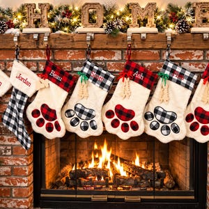 May include: Seven personalized Christmas stockings hanging from a wooden mantel. The stockings feature red and black or white and black buffalo plaid cuffs and paw print appliques. Each stocking is embroidered with names including Warren, Jordan, Beau, Scott, Ash, Finn, and Brock.