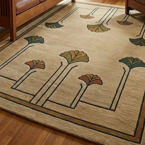 May include: A rectangular area rug with a tan background featuring a repeating pattern of stylized ginkgo leaf motifs in shades of green, orange, and brown. The design includes dark green linear borders and stems connecting the floral elements.