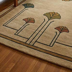 May include: A beige area rug featuring a dark brown linear border and stylized fan-shaped floral motifs in shades of teal, olive green, and burnt orange. The rug has a textured pile surface with clean geometric lines and symmetrical plant patterns.