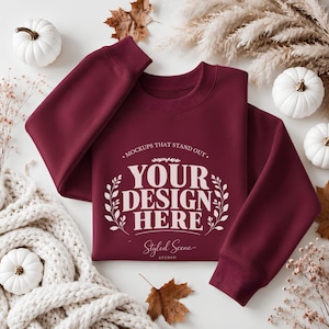Könnte beinhalten: Ein bordeauxrotes Langarm-Sweatshirt mit einem weißen Grafikdruck, der MOCKUPS THAT STAND OUT YOUR DESIGN HERE und Styled Scene Studio liest. Das Kleidungsstück hat einen Rundhalsausschnitt und gerippte Bündchen, flach ausgelegt.