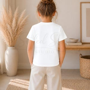 Puede incluir: Un ni&ntilde;o con una camiseta blanca y pantalones color beige. La camiseta tiene el texto "Styled So" y "STUDIO" impreso. El ni&ntilde;o est&aacute; de espaldas a la c&aacute;mara.