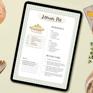 Peut inclure: Une tablette num&eacute;rique affiche une recette de tarte au citron, avec les ingr&eacute;dients et les instructions. Des cuill&egrave;res en bois et une fourchette sont pos&eacute;es &agrave; proximit&eacute;, ainsi qu'un cadeau emball&eacute; et une branche d'herbes. Un pain est visible en arri&egrave;re-plan.