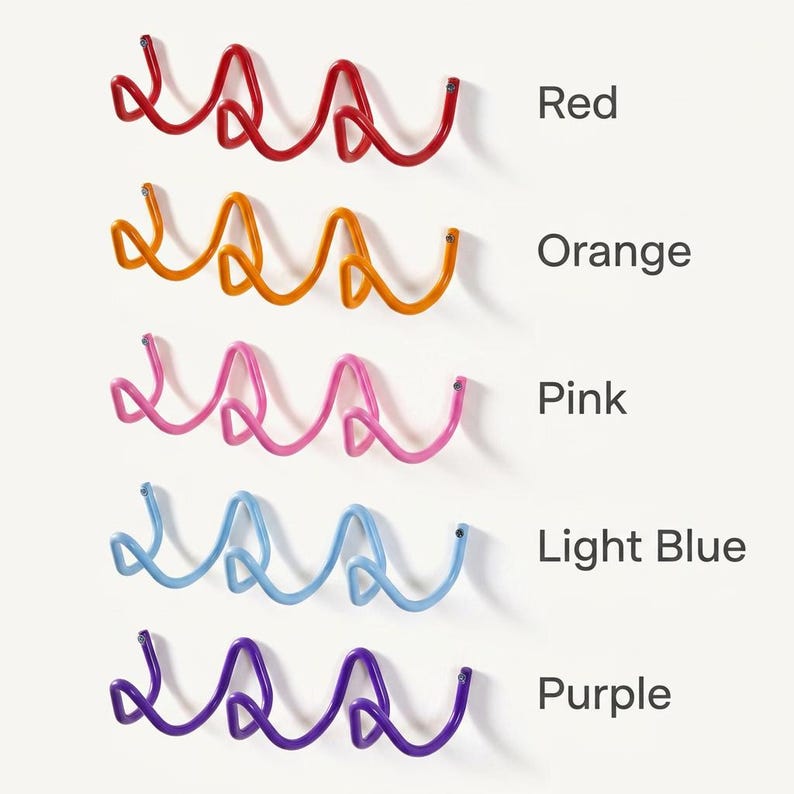 May include: Five colorful, wavy metal wall hooks in red, orange, pink, light blue, and purple. Each hook is mounted on a white wall. Text labels identify each color.