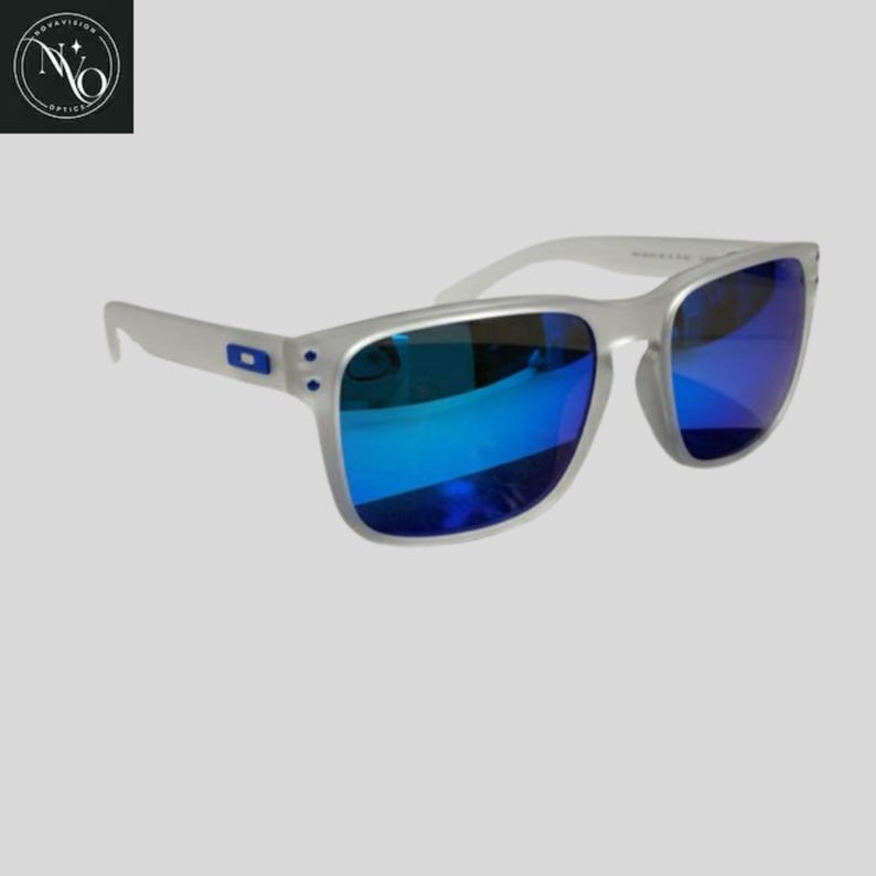 May include: Clear-framed sunglasses with blue mirrored lenses. The sunglasses have a square shape and a small blue logo on the temple. The lenses reflect a bright blue color.
