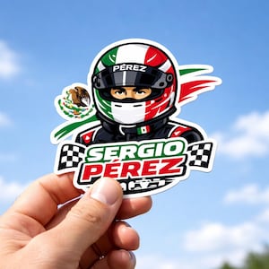 May include: A sticker featuring a cartoon illustration of a race car driver wearing a helmet with the colors of the Mexican flag. The sticker has the name "Sergio Pérez" in red and green text, with a checkered flag design.
