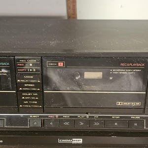 May include: A black Pioneer double cassette deck featuring two tape compartments, a digital tape counter, and various control buttons for playback and recording. The front panel includes labels for Dolby NR, tape selector, and record level adjustments.