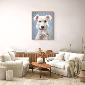 Op de afbeelding: Een ingelijste kunstdruk met een olieverfschilderij van een witte hond met een textuurrijke vacht en donkere ogen tegen een lichtblauwe achtergrond. Het kunstwerk zit in een eenvoudige houten lijst en toont zichtbare penseelstreken.