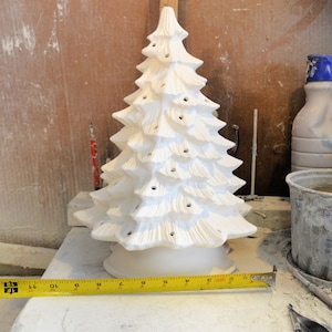 May include: White ceramic Christmas tree with holes for lights. The tree is 11 inches tall and has a base that is 6 inches in diameter.