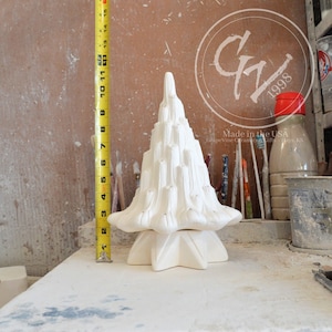 May include: White ceramic Christmas tree with a star-shaped base. The tree is approximately 30 cm tall. Made in the USA. Grapevine Ceramics Gifts - Hays, KS.