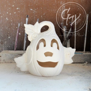 May include: White ceramic pumpkin with a carved smiling face and leaf accents. The pumpkin is ready to be painted.