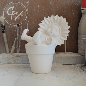Puede incluir: Figurilla de cerámica blanca de un niño con un sombrero de girasol y tumbado boca abajo en una maceta. La figurita está sin pintar y lista para ser decorada.