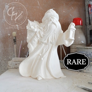 Puede incluir: Figura de cerámica blanca de Papá Noel sosteniendo una linterna. Lleva una túnica larga y tiene una larga barba blanca. La figura está marcada con "RARE".