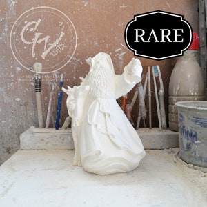 Puede incluir: Figura de cerámica blanca de Papá Noel sosteniendo una linterna y un reno. La figura está marcada con "Rare" y "Made in the USA".