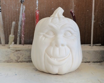 May include: White ceramic pumpkin with a carved face, grinning with a toothy smile. The pumpkin is unpainted and ready to be decorated.
