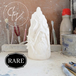 May include: White ceramic figurine of a bearded man with a pointed hat, standing in a tree trunk. The figurine is unpainted and ready to be decorated. The figurine is labeled "RARE".