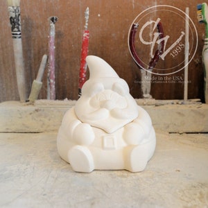 May include: White ceramic gnome figurine with a beard and a hat. The gnome is sitting with its hands in its lap. The figurine is unpainted and ready to be decorated.