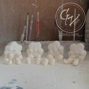 以下が含まれることがあります： 笑顔の顔が付いた、未完成の雲の形をしたセラミックフィギュアが4つ。それぞれに手と靴がついています。フィギュアは白く、白い表面に置かれています。画像にはツールと「Made in the USA」のロゴも表示されています。