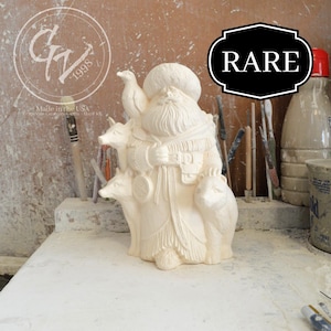 Puede incluir: Figura de cerámica blanca de un hombre barbudo con un sombrero y abrigo de piel, sosteniendo un pájaro y dos zorros. La figura está etiquetada como "RARE".
