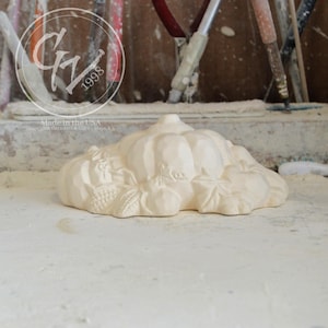 Puede incluir: Una calabaza de cerámica blanca con un diseño detallado de hojas y otros elementos de la cosecha de otoño. La calabaza es una pieza decorativa y está hecha en los Estados Unidos.