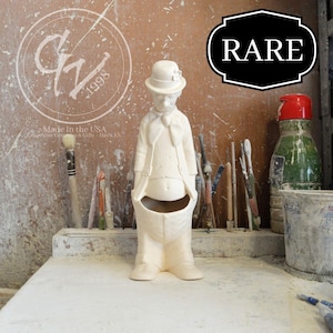 May include: White ceramic figurine of a man wearing a hat and a bow tie. The figurine is standing with its hands in its pockets. The figurine is a vintage piece and is marked "Rare".