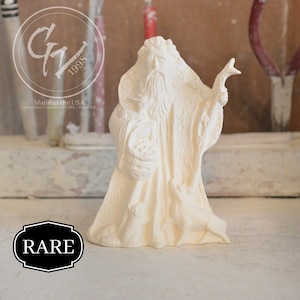 May include: White ceramic figurine of a bearded man holding a basket and a staff. The figurine is labeled "RARE" and "Made in the USA Grapevine Ceramics & Gifts - Hays, KS".