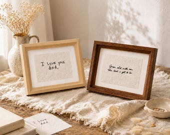 May include: Two framed art pieces with handwritten text. One reads "I love you dad." in a light wood frame. The other says "Grow old with me, the best is yet to be" in a dark wood frame. A small card with the text "I love dad" is also visible.