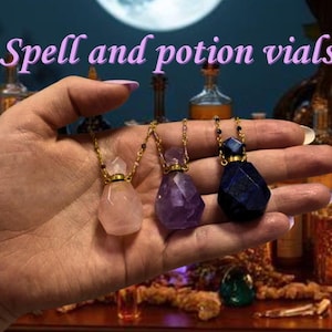 May include: Three spell and potion vials in a hand. The vials are made of rose quartz, amethyst, and a dark blue stone. Each vial has a gold-colored cap and chain. The background includes bottles, candles, and the text "Spell and potion vials".