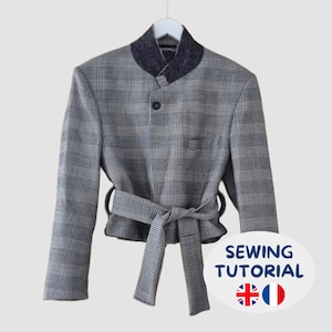 Könnte beinhalten: Eine grau-schwarze karierte Jacke mit Stehkragen, einem Knopfverschluss und einem passenden Bindegürtel in der Taille. Das Kleidungsstück hat eine Brusttasche und lange Ärmel. Eine weiße ovale Grafik unten zeigt den Text SEWING TUTORIAL.