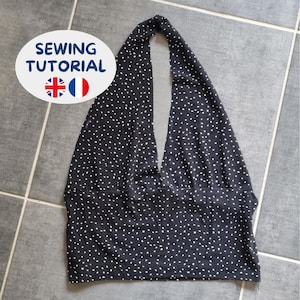 May include: A black halter top featuring a white polka dot pattern throughout. The garment has a deep V-neckline and a wide horizontal band at the waist. An oval graphic overlay in the upper left corner displays the text SEWING TUTORIAL.