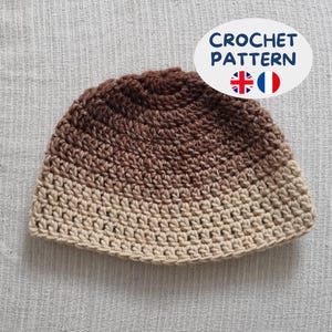 Puede incluir: Un gorro de ganchillo con un degradado de color que va desde el marrón oscuro en la coronilla hasta un beige claro en el borde. Un gráfico ovalado en la esquina superior derecha muestra el texto CROCHET PATTERN con banderas británica y francesa.