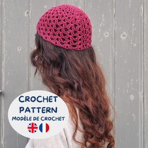 Pode incluir: Um gorro de crochê cor magenta profundo com um padrão de pontos abertos. Uma sobreposição gráfica circular branca exibe o texto "CROCHET PATTERN" e "MODÈLE DE CROCHET" juntamente com as bandeiras do Reino Unido e da França no canto inferior.