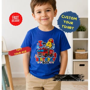 Peut inclure: Un t-shirt bleu avec un motif graphique coloré représentant un camion de pompiers rouge, le texte "I'm 4" et "Birthday Boy". Le t-shirt porte le texte "Text Your Age" et "Custom Your Tshirt" sur l'image.