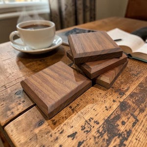 May include: A set of three ceramic mugs with a speckled, matte finish. The mugs are in shades of cream, light gray, and dark gray. Each mug has a simple, minimalist design and a rounded handle.