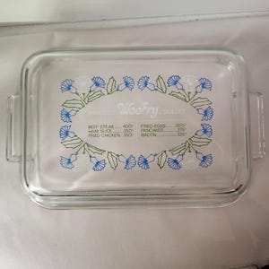 Könnte beinhalten: Transparenter Glasdeckel für eine Bratpfanne mit blau-grünem Blumendesign. Der Deckel trägt den Schriftzug "WeeFry Skillet" und Kochtemperaturen in Fahrenheit für verschiedene Lebensmittel.