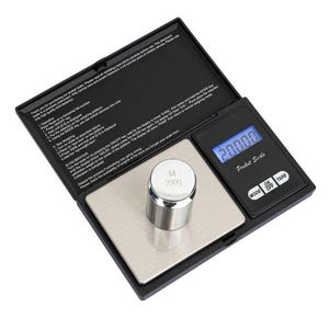 May include: A black digital pocket scale with a silver metal weighing platform and a blue backlit LCD screen displaying 200.00. A cylindrical 200g calibration weight sits on the platform. The lid features printed operating instructions.