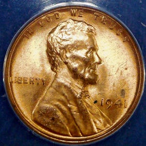 May include: A copper-colored 1941 Lincoln cent coin featuring the profile of Abraham Lincoln facing right. The text IN GOD WE TRUST is arched along the top edge, the word LIBERTY is on the left, and the year 1941 is printed on the right side.